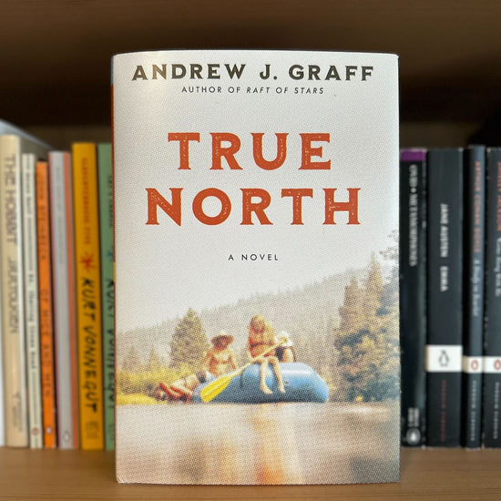 Load image into Gallery viewer, A copy of TRUE NORTH by Andrew J. Graff, in front of a background of paperback books
