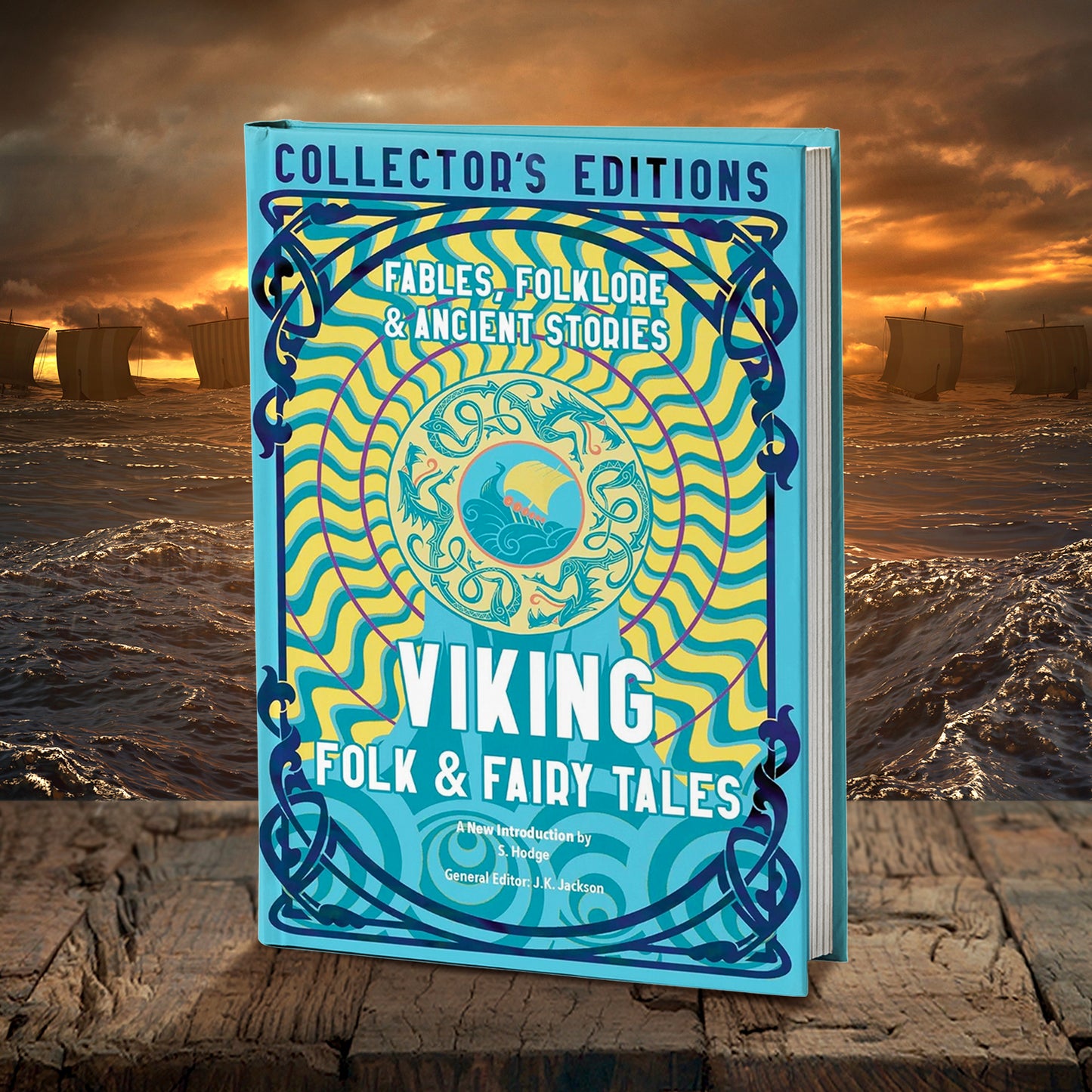 A blue and yellow book on a wood table. At the top is dark blue text saying "collector's editions." Under the text is a yellow and blue nordic drawing of a ship on the water, encircled by sea serpents and wavy blue and yellow lines. White text says "viking folk & fairy tales." Behind the book is the open ocean under an orange sky, with Viking boats at full sail.
