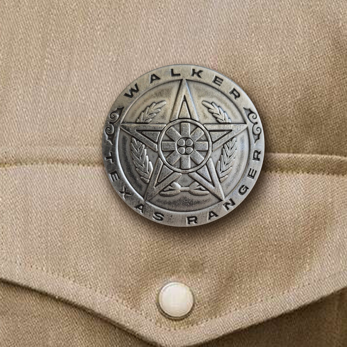 A brass pin in the shape of a sheriff's badge, attached to a tan shirt pocket. Around the edge is text saying "Walker: Texas Ranger."