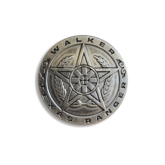 A brass pin in the shape of a sheriff's badge. Around the edge is text saying "Walker: Texas Ranger."