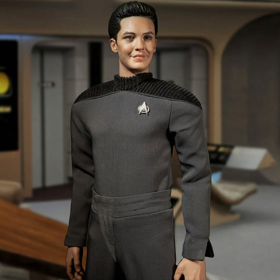 An action figure depicting the character Wesley Crusher from the TV series "Star Trek: The Next Generation." The figuring is dressed in Wesley's iconic grey uniform. In the background is the bridge of the Starship Enterprise 1701-D.