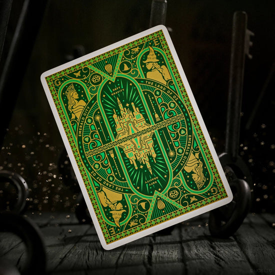 A green and gold playing card, depicting scenes from Wicked.