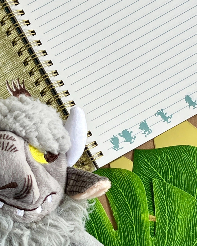A page from the book with blank lines. At the bottom are green silhouettes of some of the characters. Next to the book is a goat puppet.