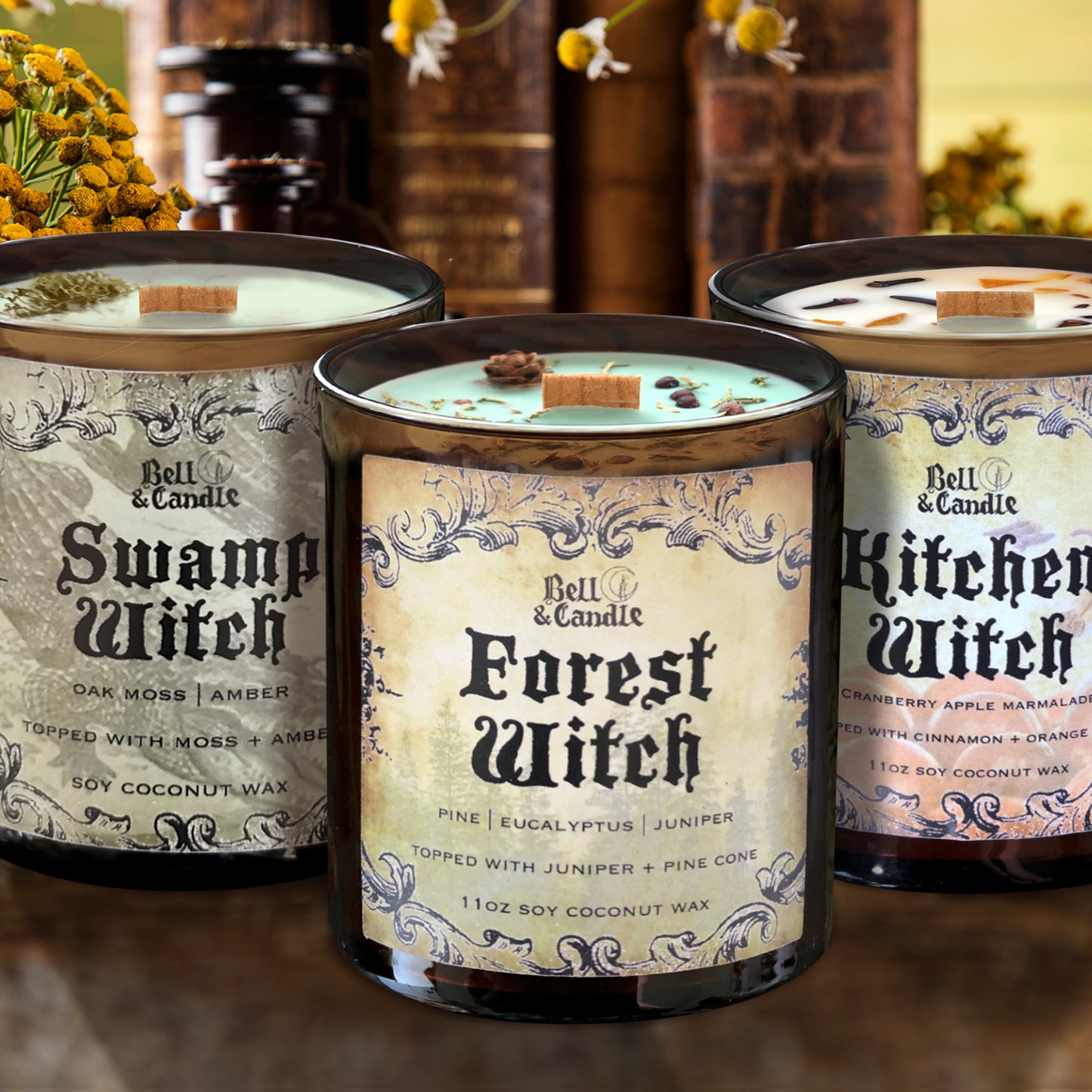 Three candles with labels 'Swamp Witch', 'Forest Witch', and 'Kitchen Witch' on a wooden surface.