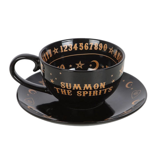 Black cup and saucer set with gold text and symbols on a white background