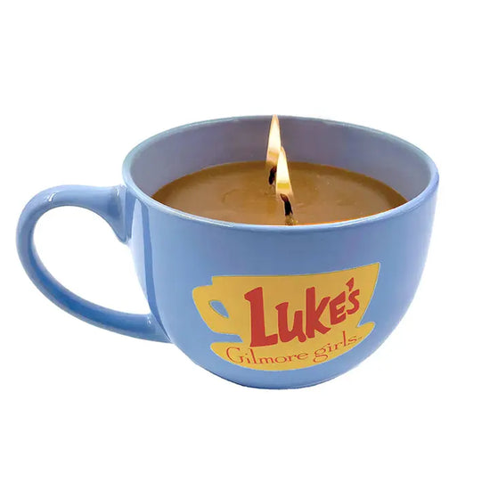 A blue mug with "Like's Diner, gilmore girls" in red on the side. Inside the mug is a lit coffee-colored candle.