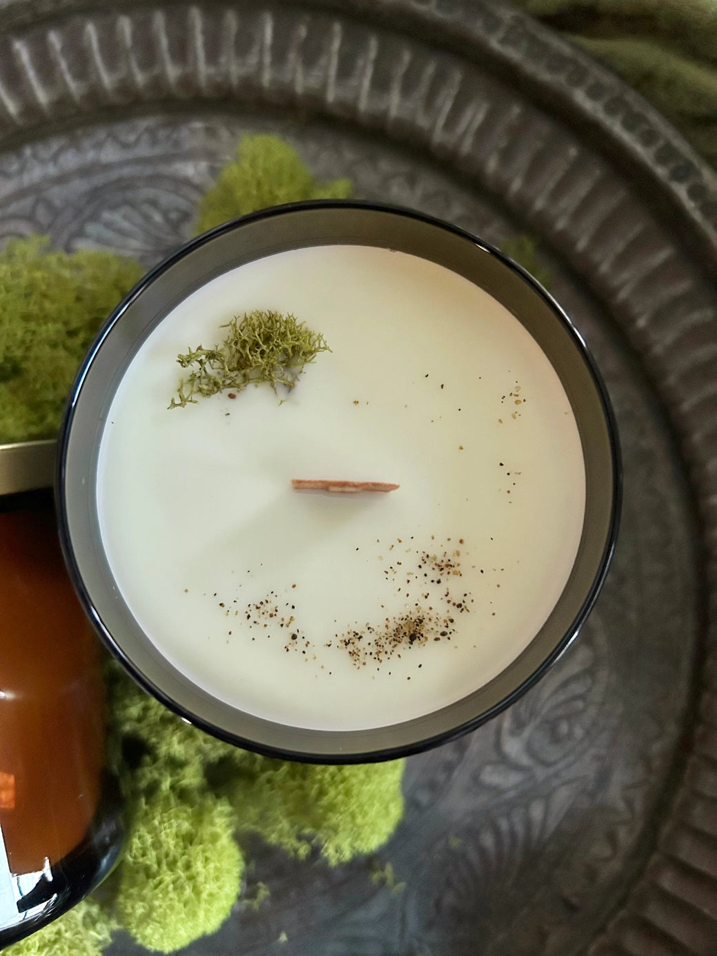 Candle with decorative elements on a pewter tray