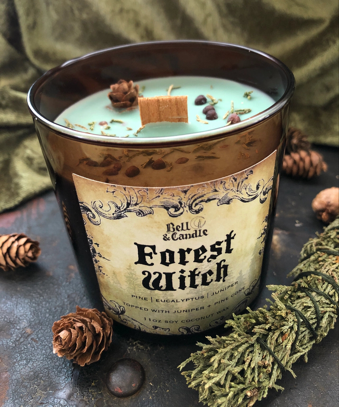 Candle labeled 'Forest Witch' with decorative elements on a dark surface