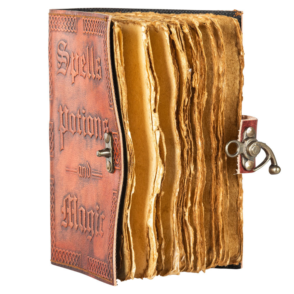 A reddish-brown, leathery journal on a white background. The front cover has raised text saying "spells, potions, and magic." At the right side is a metal locking clasp. Ragged, antique-looking pages are visible inside the journal.