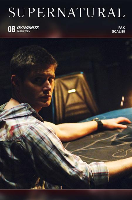 Dean from 'Supernatural' sitting at a table with a dark background