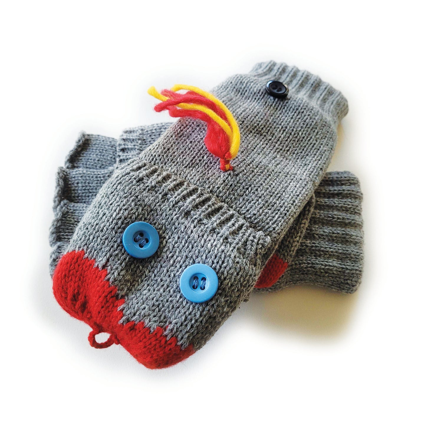 A set of knit grey flip-top mittens, each with two blue button 'eyes' sewn onto the flip top. Red yarn forms a sock puppet 'mouth' at the top and there is red-and-yellow yarn 'hair' sewn below the knuckles. 