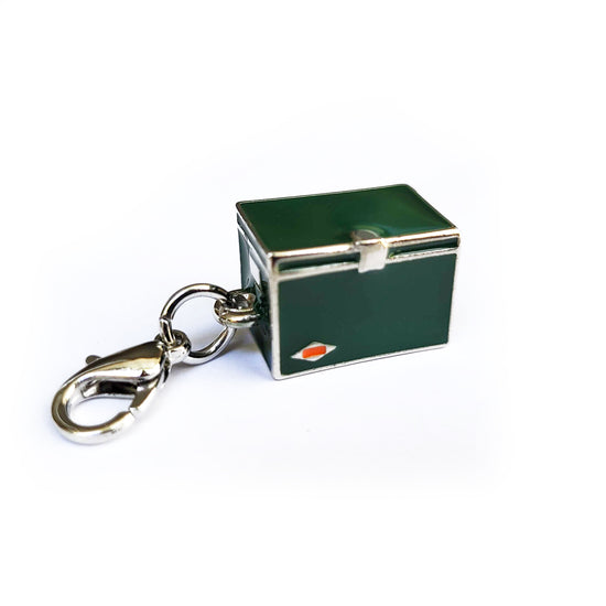 Front view of a metal charm in the shape of a vintage cooler, with the sides painted green.