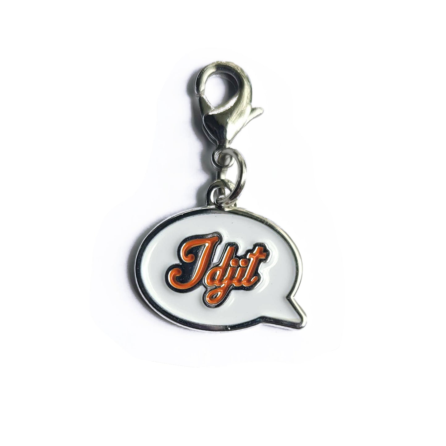 A silver charm with a keychain clasp with a white front in the shape of a speech bubble. The word "Idjit" is written in orange script font.