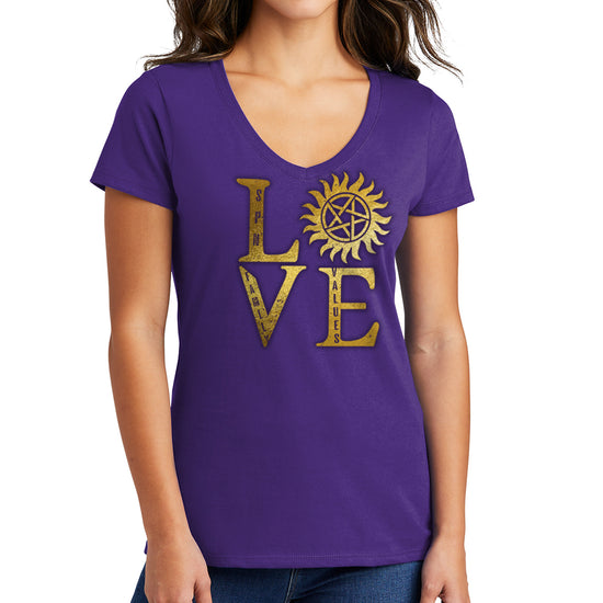 A female model wearing a purple v-neck shirt The front of the shirt has gold text saying "love," with the "O" replaced by the anti-possession symbol.