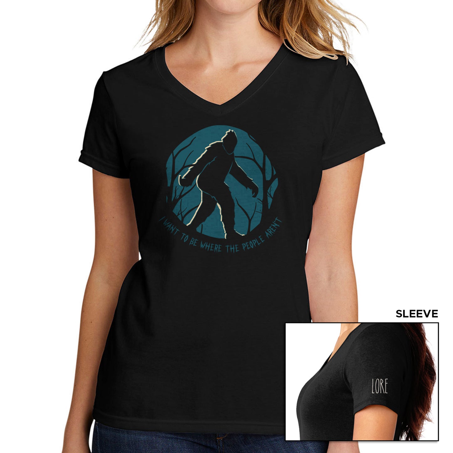 A female model wears a black v-neck t-shirt with an illustration of a bigfoot walking with a title adorning it that says "I want to be where the people aren't". The left shoulder has the word LORE written in white.