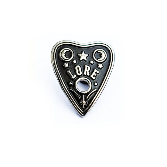 Load image into Gallery viewer, A silver enamel pin in a triangular shape resembling a OUIJA planchette with stars and two crescent moons, which reads LORE in tall, skinny white font
