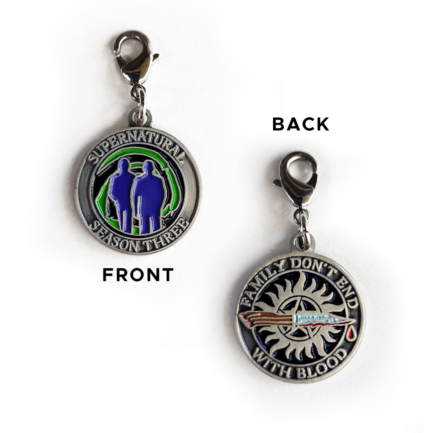 A brass coin charm with "Supernatural season three", a green "Mystery Spot" swirl, and 2 male sillhouettes on one side and "Family Don't End With Blood" with a knife and anti-possession symbol on the other.