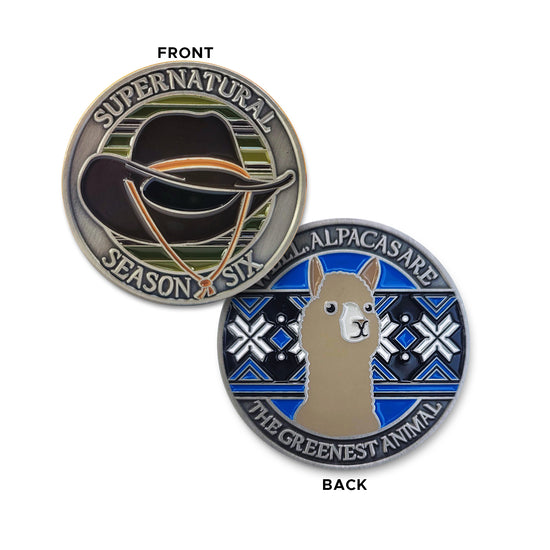 A brass coin charm with "Supernatural season six", a cowboy hat against a multicolor background on one side and "Well, alpacas are the greenest animal" with an alpaca over a blue, black and white patterned background on the other.