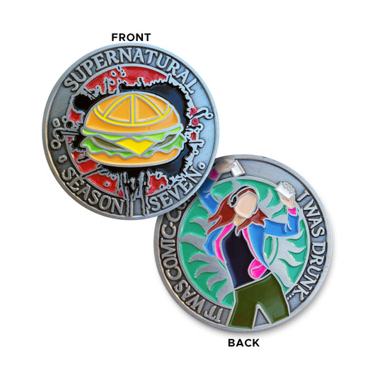 A brass coin charm with "Supernatural season seven" and a burger against a red and black background on one side and "It was comic-con. I was drunk." with teal background, an anti-possession symbol, and a sillhouette of Charlie Bradbury on the other.