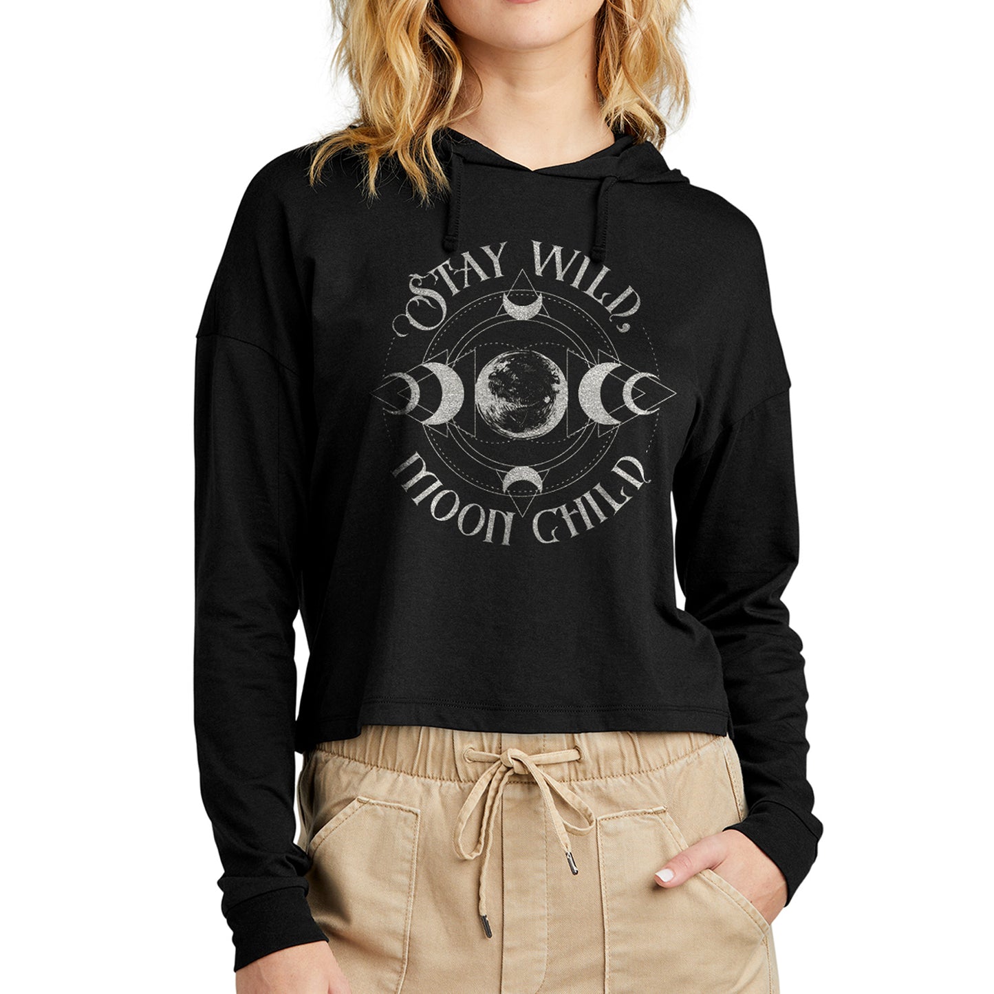 A female model wearing a black long sleeve T-shirt with silver text saying "Stay Wild Moon Child." There is a depiction of the Moon in the center, with crescent Moon phases at top, bottom, left, and right of the center. There are thin circles around the moon phases, connecting them to each other.