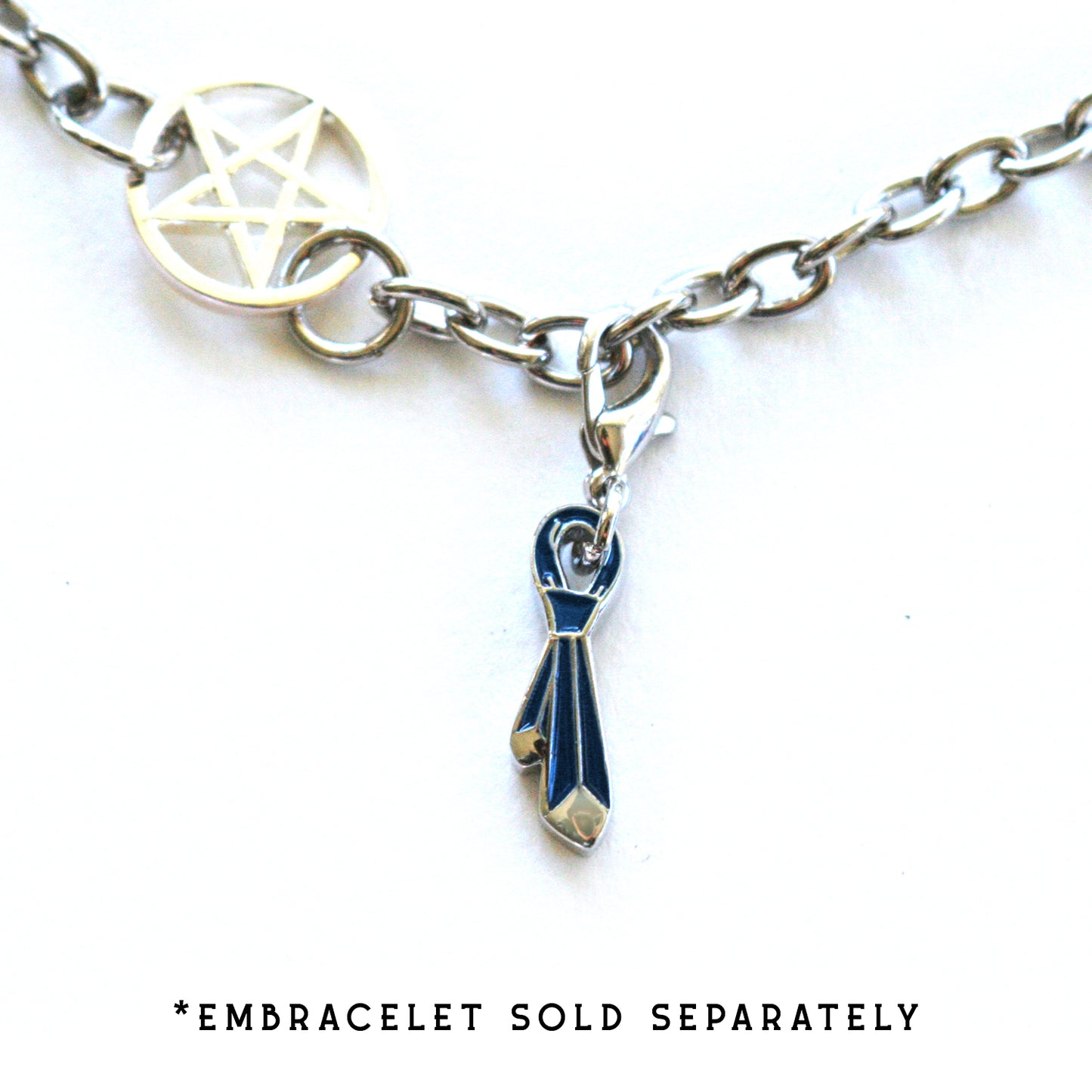 A silver charm in the shape of a backwards tie with a tiny clasp attached to a bracelet with "embracelet sold separately."