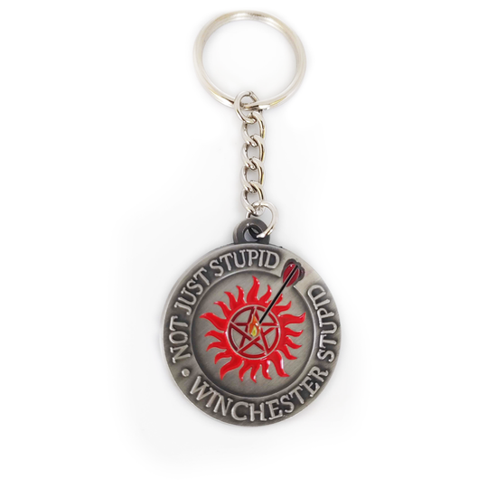 A flat keychain charm that says "Not just stupid, Winchester stupid" with an anti-possession symbol and a flaming arrow shot into the middle of it. Art by Charlotte Hill.